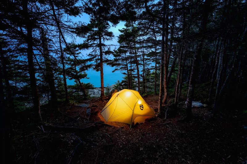 Illuminated tent above the coast at dusk