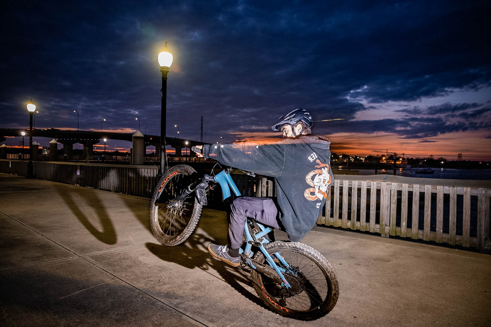 Cyclist wheelie on the waterfront at dusk