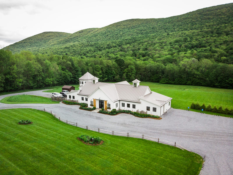Aerial view of an event venue building surrounded by green mountains