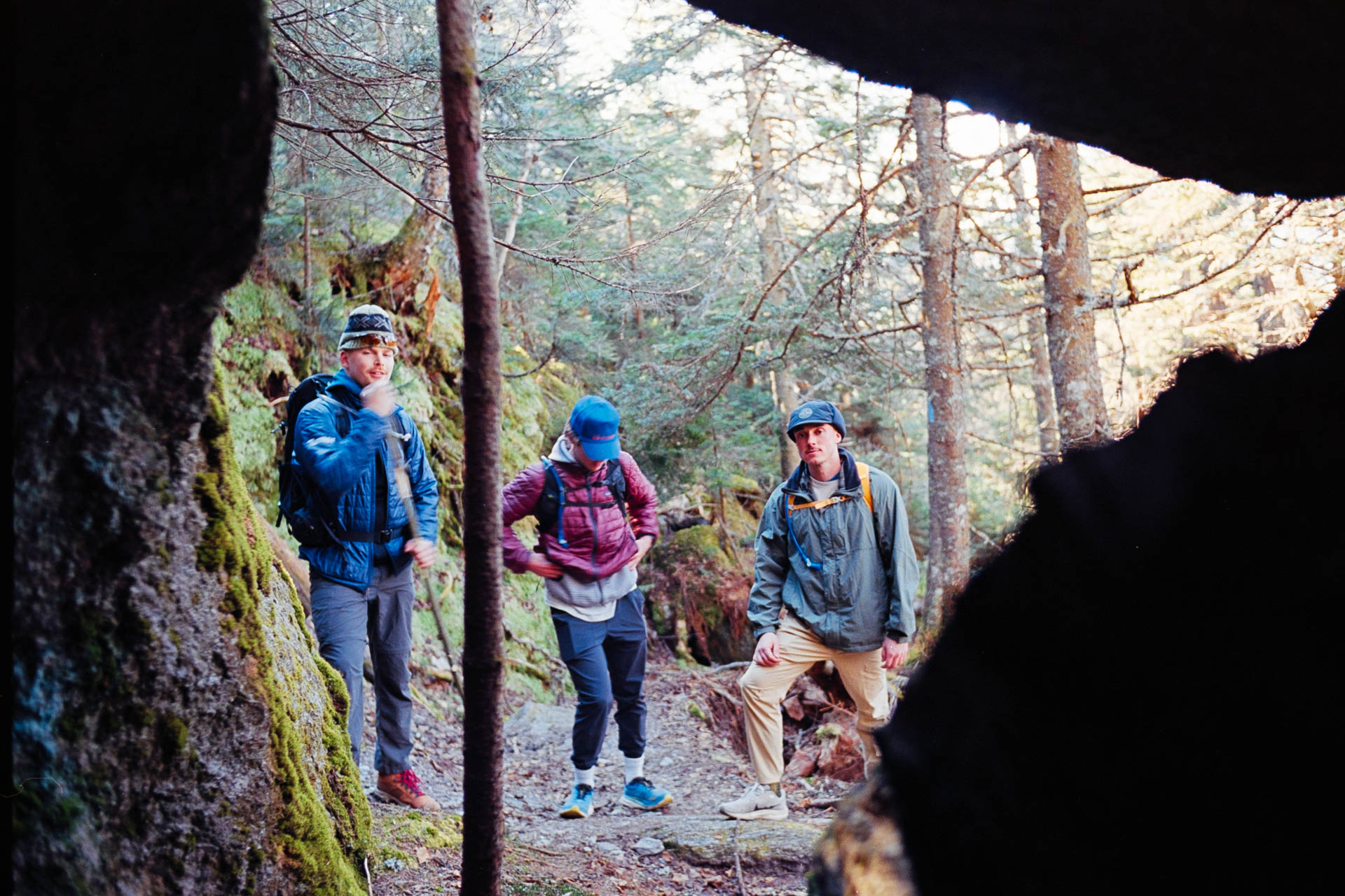 Hikers resting under mossy boulders