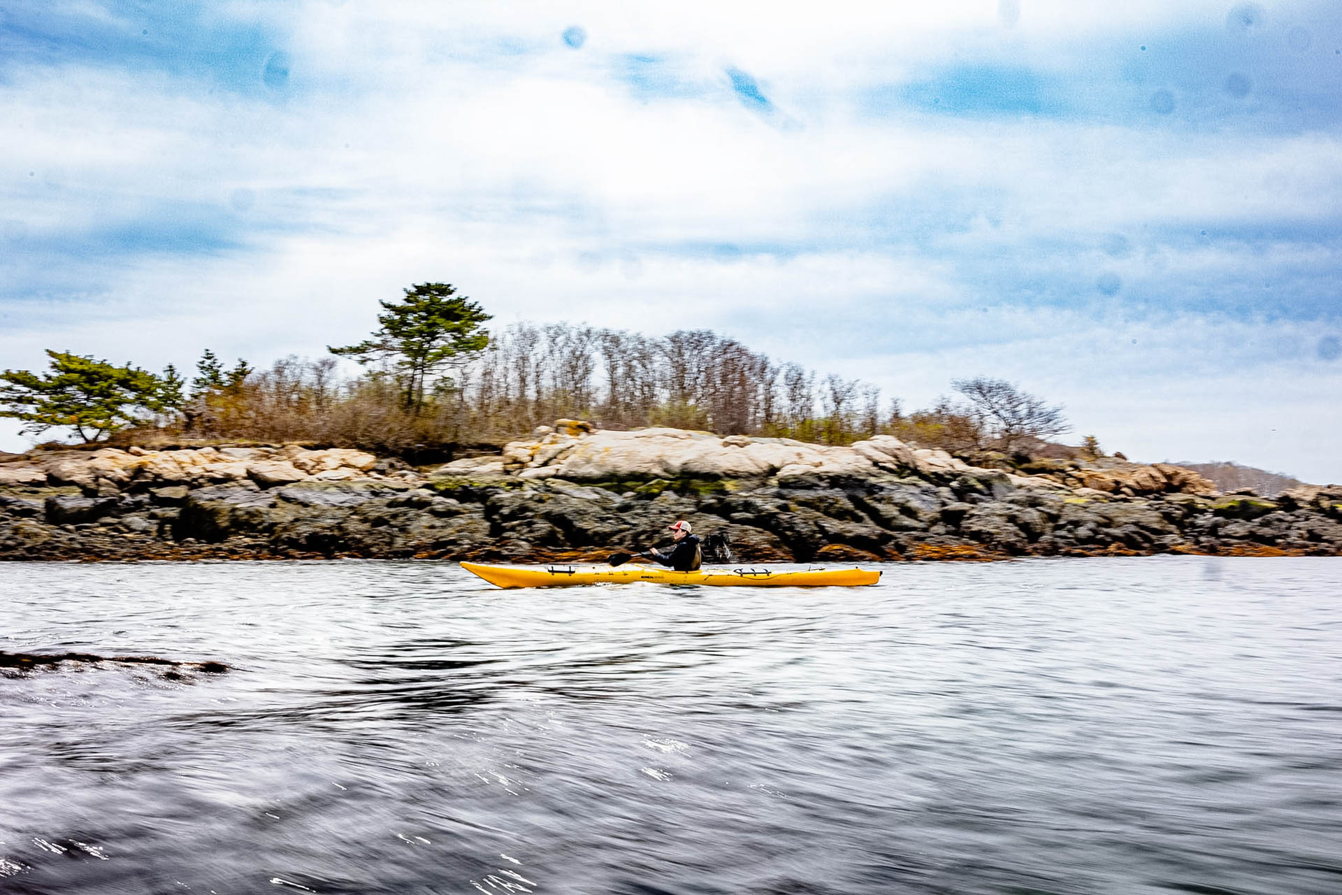 Sea kayaker passing a rocky island